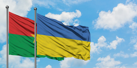 Burkina Faso and Ukraine flag waving in the wind against white cloudy blue sky together. Diplomacy concept, international relations.