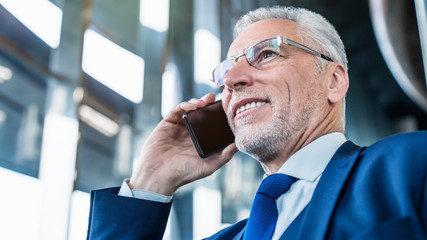 Close up shot of senior smiling man making a phone call at office