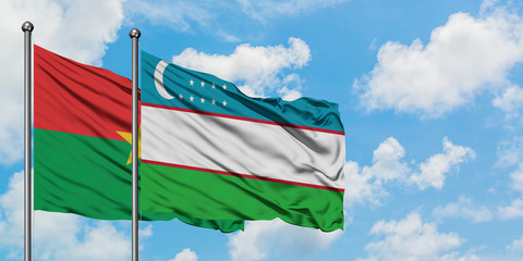 Burkina Faso and Uzbekistan flag waving in the wind against white cloudy blue sky together. Diplomacy concept, international relations.