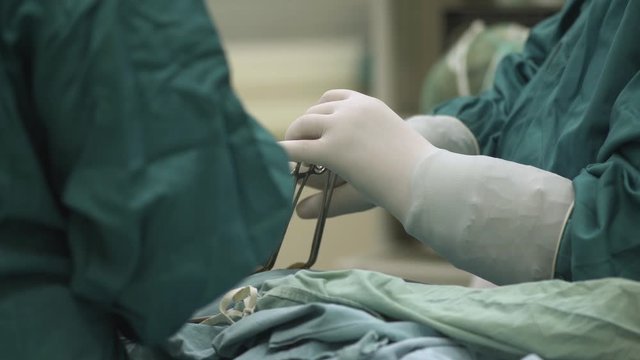 Hands of a surgeon while installing a camera through the patient's stomach during surgical operation in the operating room.