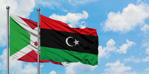 Burundi and Libya flag waving in the wind against white cloudy blue sky together. Diplomacy...