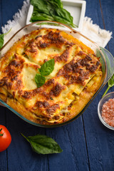 Tasty lasagna, italian cuisine. Pasta. Vertical frame with ingredients. On blue wooden background