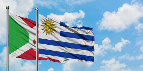 Burundi and Uruguay flag waving in the wind against white cloudy blue sky together. Diplomacy...