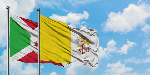 Burundi and Vatican City flag waving in the wind against white cloudy blue sky together. Diplomacy concept, international relations.