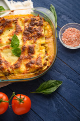 Tasty lasagna, italian cuisine. Pasta. Vertical frame with ingredients. On blue wooden background