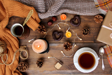 beautiful flat on an old wooden background, a cup of tea and sweets, coffee, candles, a gift in paper, cones, top view, the concept of Christmas and New Year, cozy home, close-up