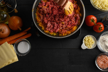 cooking Italian lasagna, preparing dressing for lasagna with ground beef and vegetables, Italian cuisine. Roasting in a pan, black background for design. Recipe book, menu, restaurant, Top view