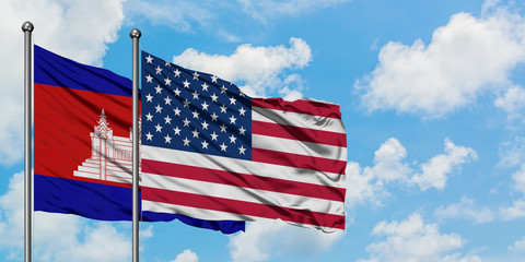 Cambodia and United States flag waving in the wind against white cloudy blue sky together. Diplomacy concept, international relations.