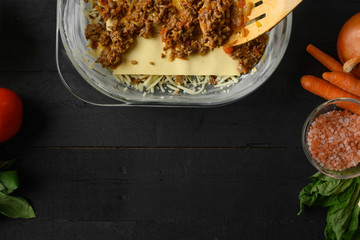 Cooking Italian lasagna, layering, vegetables and mazarella cheese. Background for design. Top view cooking process.