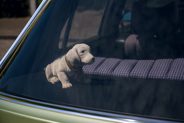 bobblehead dachshund, in german wackeldackel, on the parcel shelf in the car, a popular accessory...
