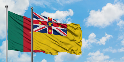 Cameroon and Niue flag waving in the wind against white cloudy blue sky together. Diplomacy concept, international relations.