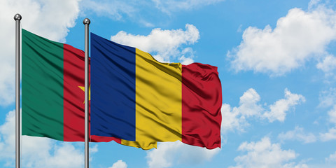 Cameroon and Romania flag waving in the wind against white cloudy blue sky together. Diplomacy...