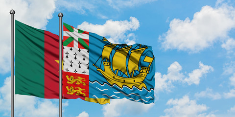Cameroon and Saint Pierre And Miquelon flag waving in the wind against white cloudy blue sky together. Diplomacy concept, international relations.