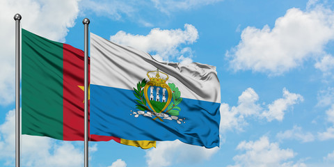Cameroon and San Marino flag waving in the wind against white cloudy blue sky together. Diplomacy concept, international relations.