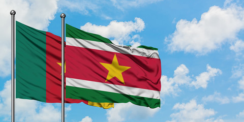Cameroon and Suriname flag waving in the wind against white cloudy blue sky together. Diplomacy...
