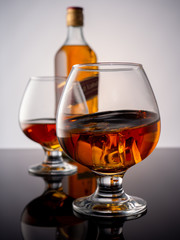 Glass of whiskey on ice with bottle on wood bar