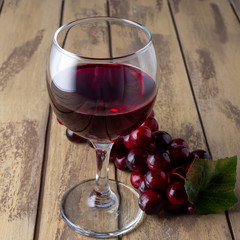 Glass of red wine and grapes on a wooden table