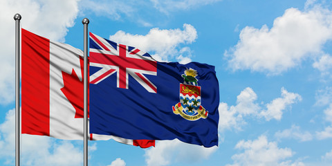 Canada and Cayman Islands flag waving in the wind against white cloudy blue sky together. Diplomacy concept, international relations.