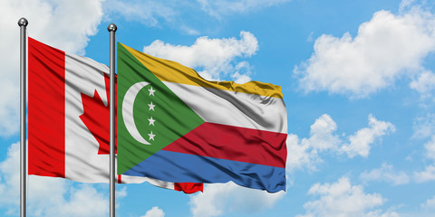 Canada and Comoros flag waving in the wind against white cloudy blue sky together. Diplomacy...