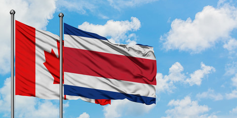 Canada and Costa Rica flag waving in the wind against white cloudy blue sky together. Diplomacy concept, international relations.