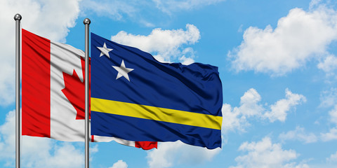 Canada and Curacao flag waving in the wind against white cloudy blue sky together. Diplomacy concept, international relations.