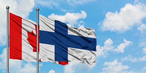 Canada and Finland flag waving in the wind against white cloudy blue sky together. Diplomacy concept, international relations.