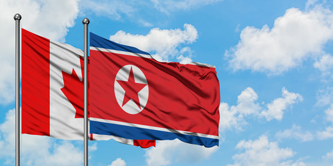 Canada and North Korea flag waving in the wind against white cloudy blue sky together. Diplomacy concept, international relations.