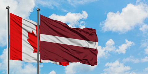 Canada and Latvia flag waving in the wind against white cloudy blue sky together. Diplomacy concept, international relations.