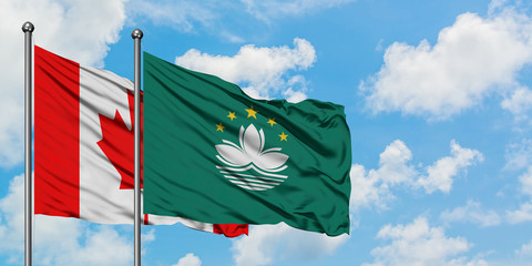 Canada and Macao flag waving in the wind against white cloudy blue sky together. Diplomacy concept, international relations.