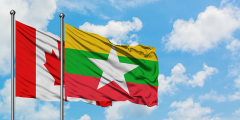 Canada and Myanmar flag waving in the wind against white cloudy blue sky together. Diplomacy...