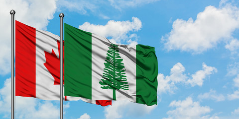 Canada and Norfolk Island flag waving in the wind against white cloudy blue sky together. Diplomacy concept, international relations.