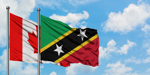 Canada and Saint Kitts And Nevis flag waving in the wind against white cloudy blue sky together. Diplomacy concept, international relations.
