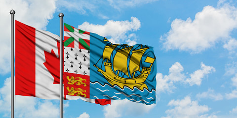 Canada and Saint Pierre And Miquelon flag waving in the wind against white cloudy blue sky together. Diplomacy concept, international relations.