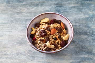 Bowl of granola with nuts and raisins. Concept for a tasty and healthy meal. Rustic wooden background. Copy space. 