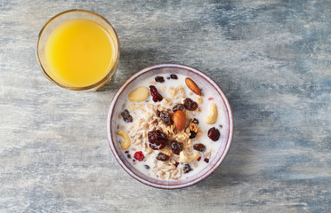 Bowl of granola with milk, nuts, raisins and cranberries. Concept for a tasty and healthy meal. Rustic wooden background. Top view. Close up. Copy space. 