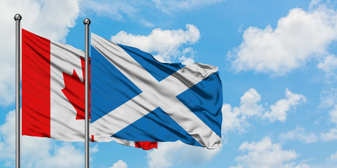 Canada and Scotland flag waving in the wind against white cloudy blue sky together. Diplomacy concept, international relations.