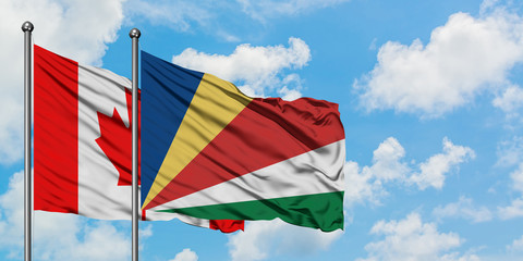 Canada and Seychelles flag waving in the wind against white cloudy blue sky together. Diplomacy concept, international relations.