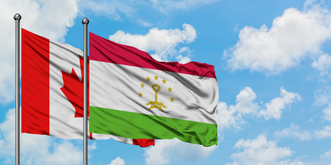 Canada and Tajikistan flag waving in the wind against white cloudy blue sky together. Diplomacy concept, international relations.