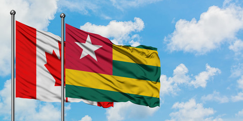 Canada and Togo flag waving in the wind against white cloudy blue sky together. Diplomacy concept, international relations.