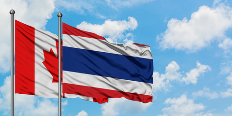 Canada and Thailand flag waving in the wind against white cloudy blue sky together. Diplomacy concept, international relations.