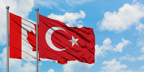 Canada and Turkey flag waving in the wind against white cloudy blue sky together. Diplomacy concept, international relations.