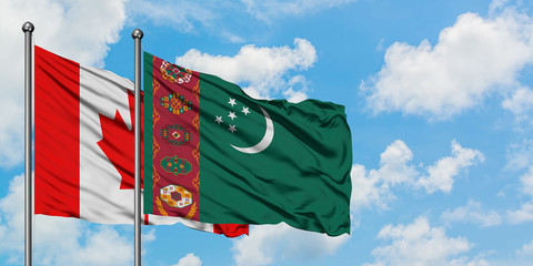 Canada and Turkmenistan flag waving in the wind against white cloudy blue sky together. Diplomacy concept, international relations.