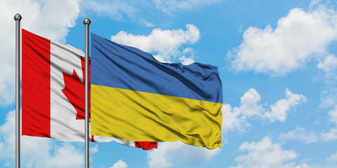 Canada and Ukraine flag waving in the wind against white cloudy blue sky together. Diplomacy concept, international relations.