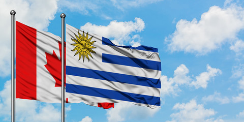 Canada and Uruguay flag waving in the wind against white cloudy blue sky together. Diplomacy concept, international relations.