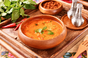 Thai red chicken curry in wooden bowl