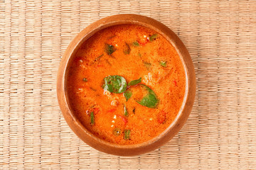 Thai red chicken curry in wooden bowl