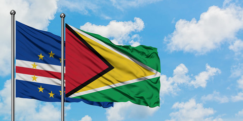 Cape Verde and Guyana flag waving in the wind against white cloudy blue sky together. Diplomacy concept, international relations.
