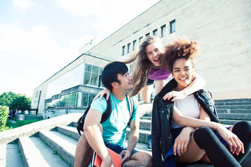 cute group of teenages at the building of university with books huggings, diversity nations real students lifestyle