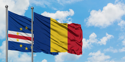 Cape Verde and Romania flag waving in the wind against white cloudy blue sky together. Diplomacy concept, international relations.