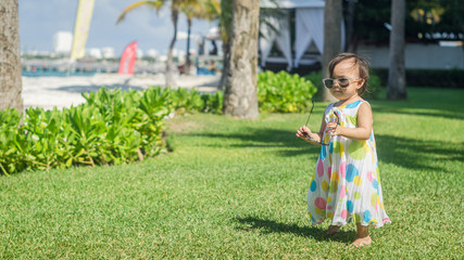 Naklejka premium Little girl in colorful dress sitting on the grass